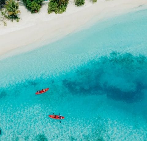 Aerial of the white sandy beaches at Nova Maldives with people on two kayaks