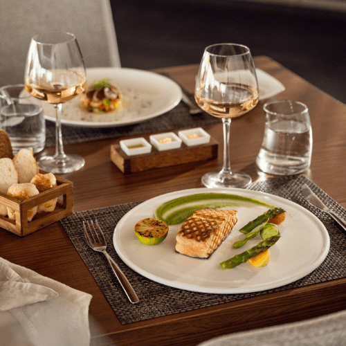 2 plates of food and two wine glasses on a table