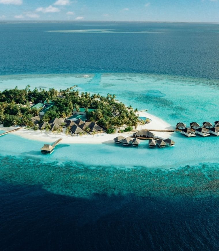 Aerial of Nova Maldives, small natural island with greenery and expansive lagoon