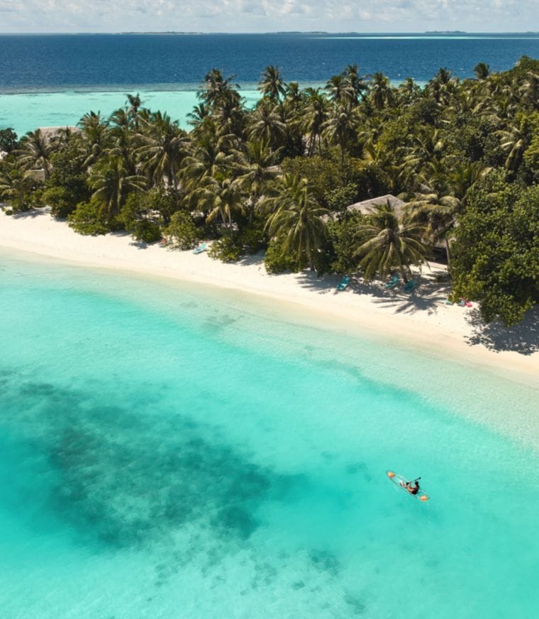 Aerial of the white sandy beaches and two people in the lagoon at Nova Maldives