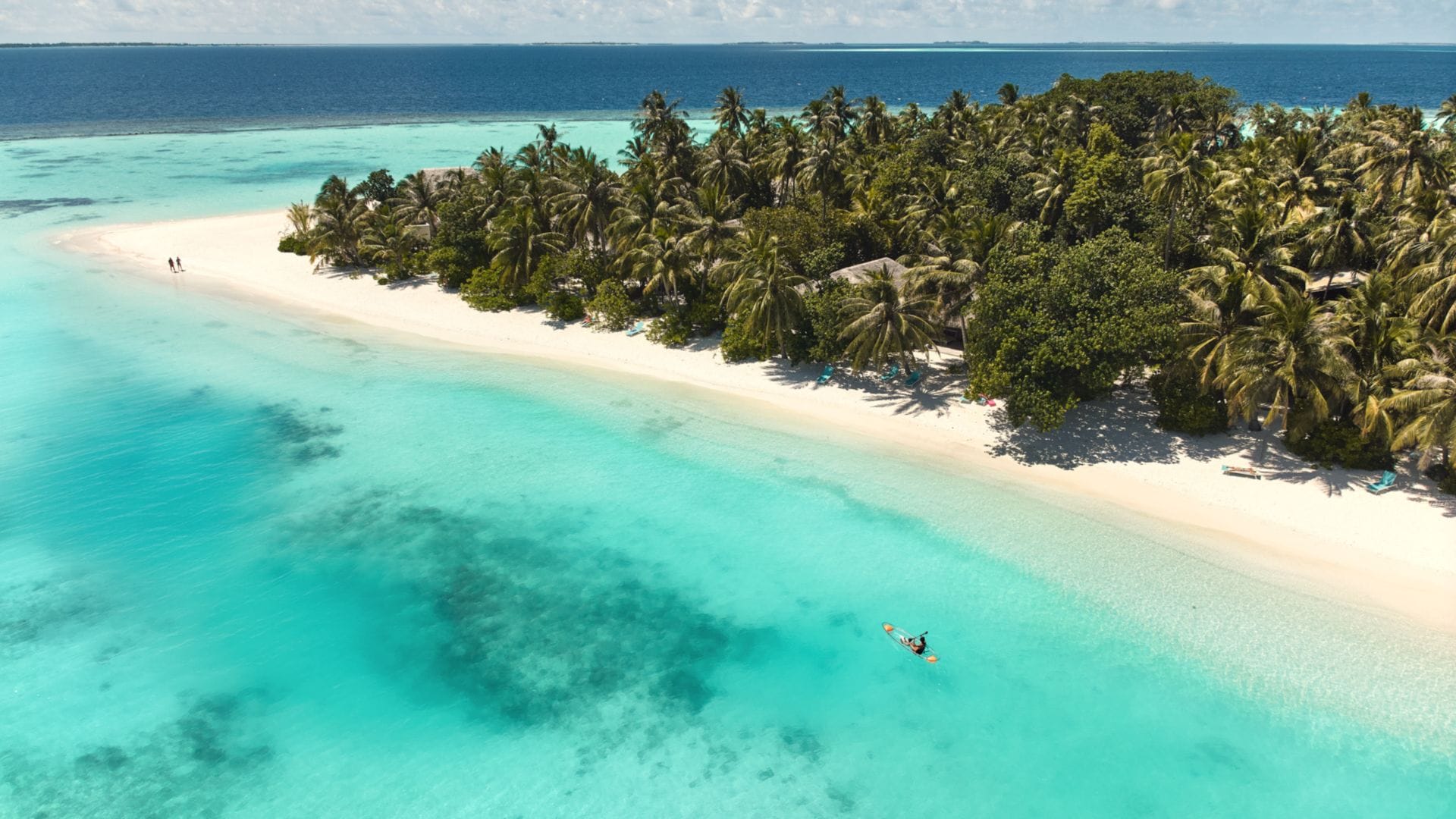 Aerial of the white sandy beaches and two people in the lagoon at Nova Maldives