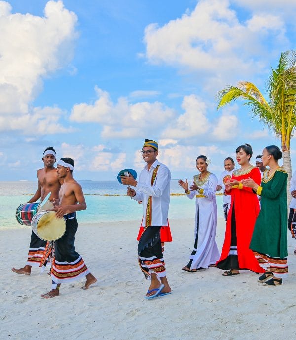 People walking on the beach wearing traditional Maldivian clothing to celebrate Eid at Nova Maldives