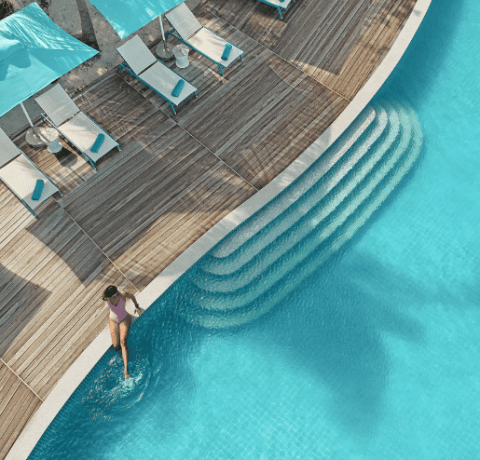 Woman sitting at the edge of the pool with her legs in the water, at Solis in Nova Maldives