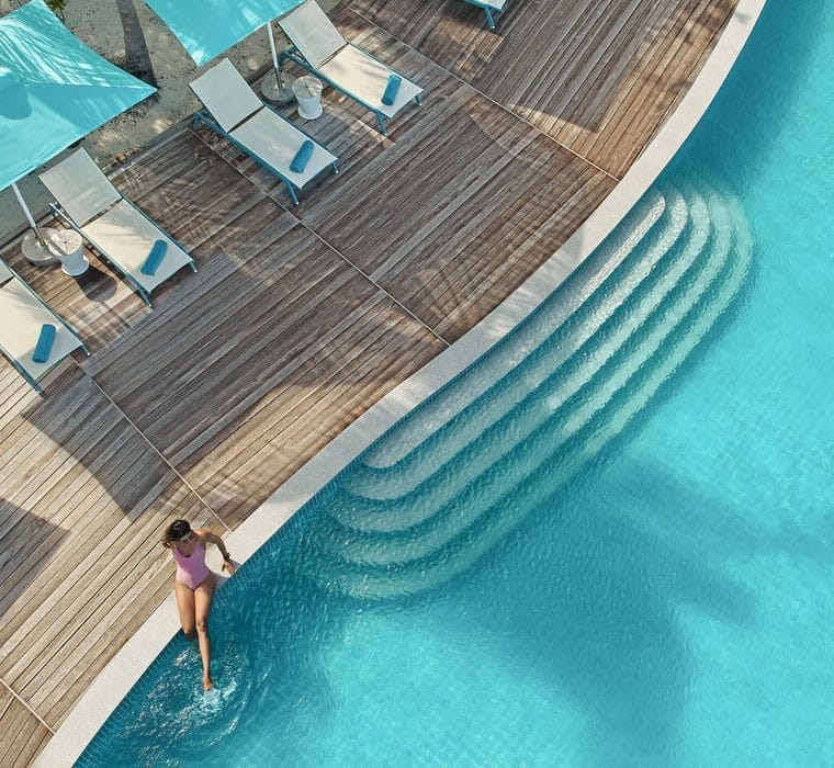 Woman sitting at the edge of the pool with her legs in the water, at Solis in Nova Maldives