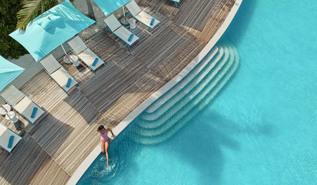 Woman sitting at the edge of the pool with her legs in the water, at Solis in Nova Maldives