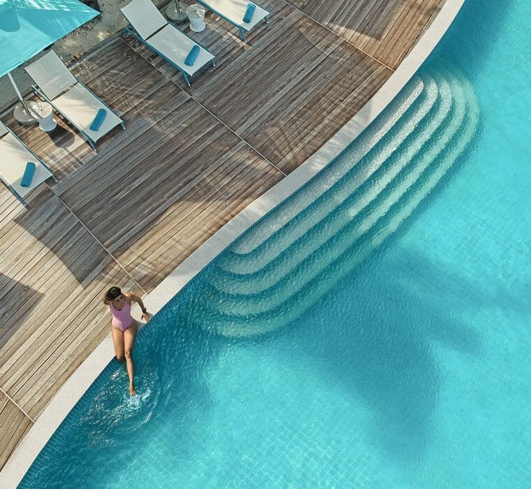 Woman sitting at the edge of the pool with her legs in the water, at Solis in Nova Maldives