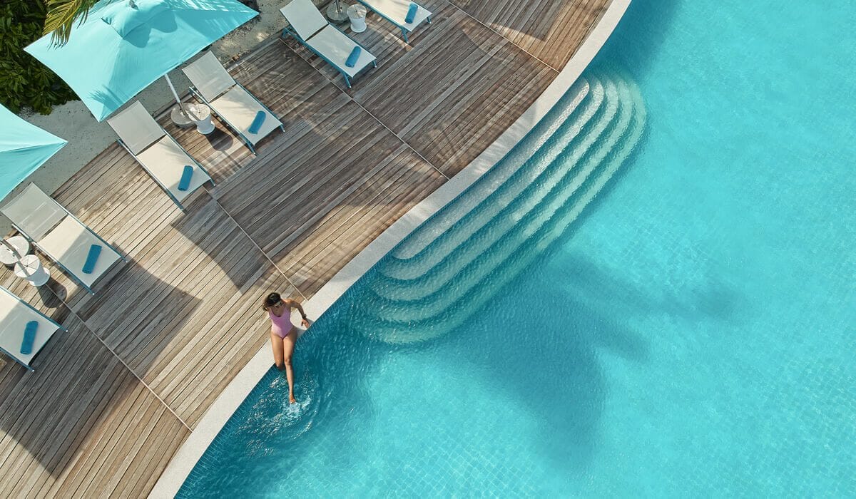 Woman sitting at the edge of the pool with her legs in the water, at Solis in Nova Maldives