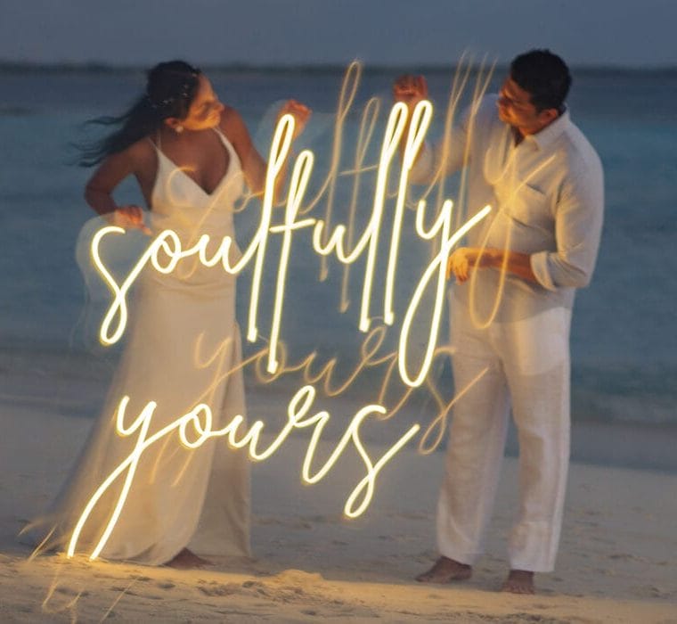 A couple holding up a sign that says "Soulfully Yours"