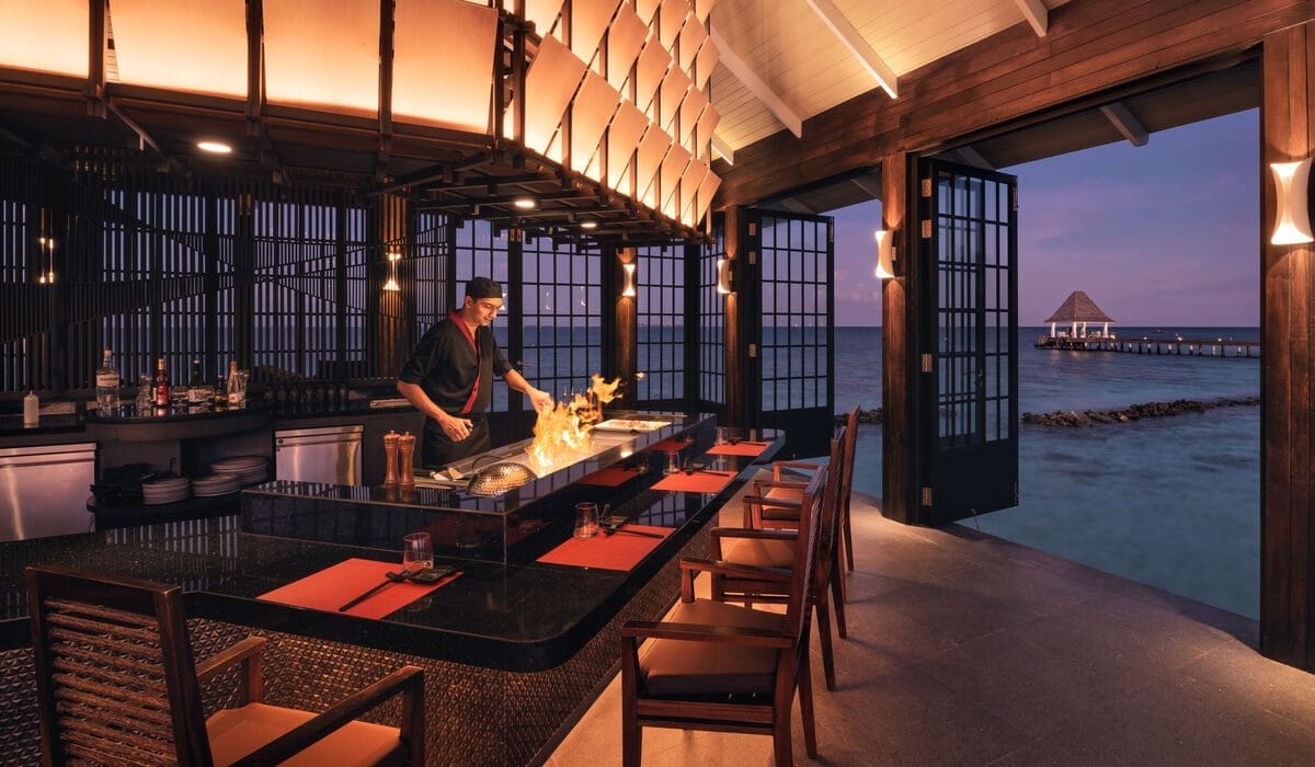 A chef lighting a fire at the teppanyaki station at Mizu, the overwater restaurant at Nova Maldives