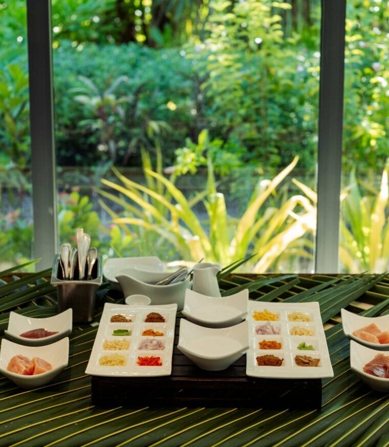 Ingredients laid out in an open-air dining area with green surroundings.