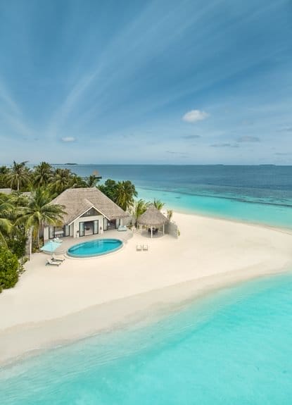 Aerial view of a beachfront villa with pool and clear waters