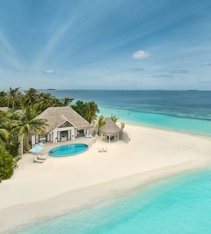 Aerial view of a beachfront villa with pool and clear waters